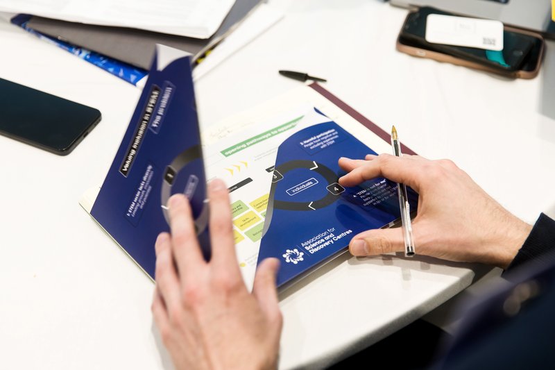 person opening a printed copy of the Theory of Change document